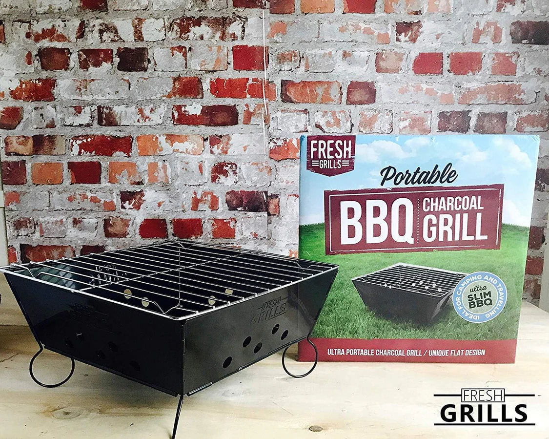 Gril à charbon portable pliable avec grille en acier inoxydable, fond noir, présenté devant un mur en briques rouges et une boîte colorée