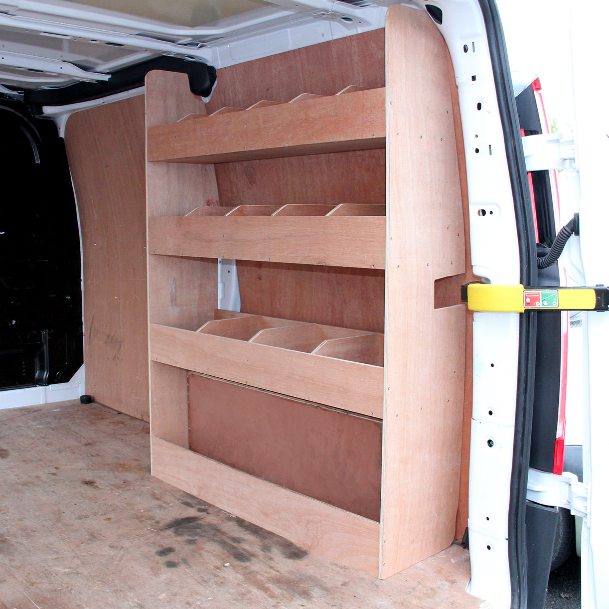 Étagères en contreplaqué brun clair, conçues pour s'adapter à l'intérieur d'un Ford Transit, offrant plusieurs niveaux de rangement pratique
