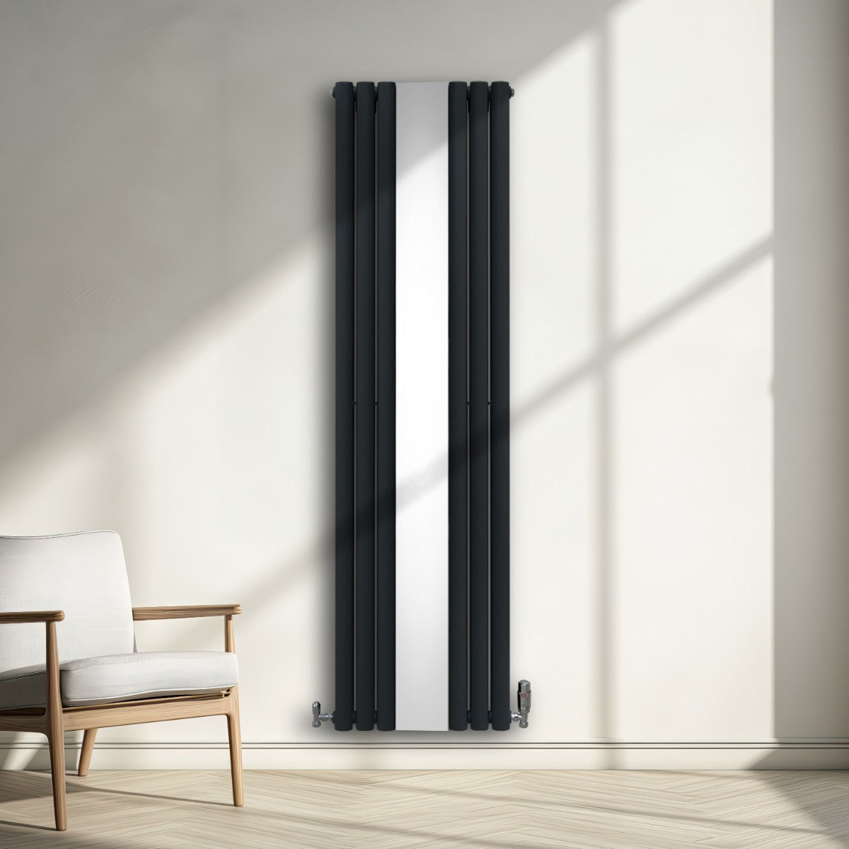 Radiateur à colonnes ovales gris anthracite avec miroir central, installé sur un mur lumineux, à côté d'un fauteuil moderne en bois