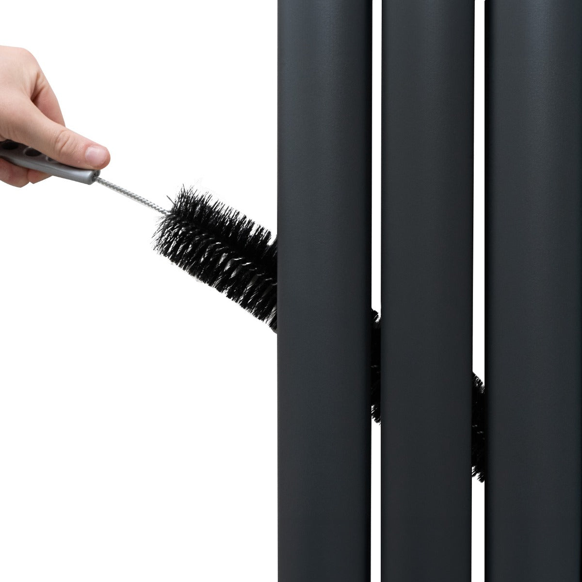 Radiateur à colonnes ovales gris anthracite avec un nettoyage en cours, brosse noire insérée entre les panneaux pour un entretien facile