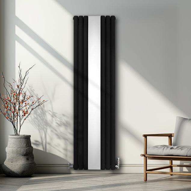 Radiateur à colonnes ovales noir avec un panneau miroir central, installé dans un intérieur moderne, éclairé par la lumière naturelle