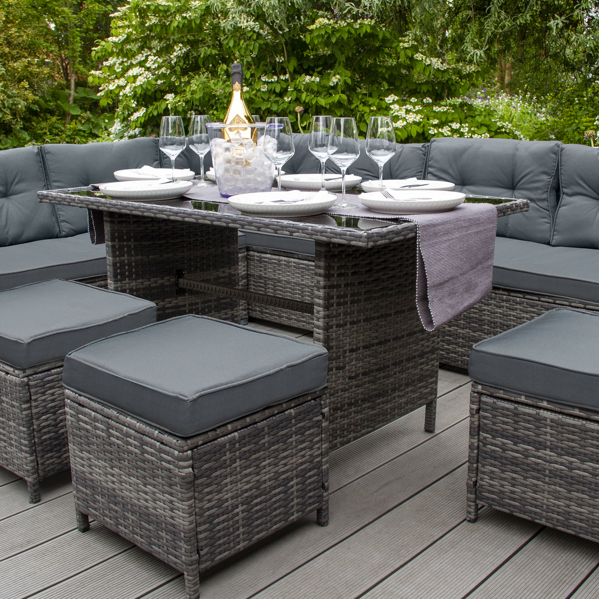 Salon de jardin en rotin gris pour 9 personnes, avec coussins gris, table centrale et chaises carrées, décoré pour un repas élégant