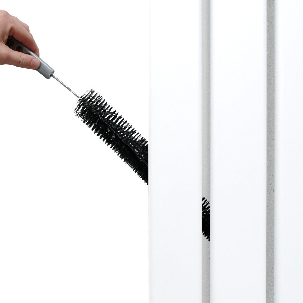 Brosse noire en train de nettoyer un radiateur plat à miroir blanc, mettant en avant sa surface lisse et son design moderne