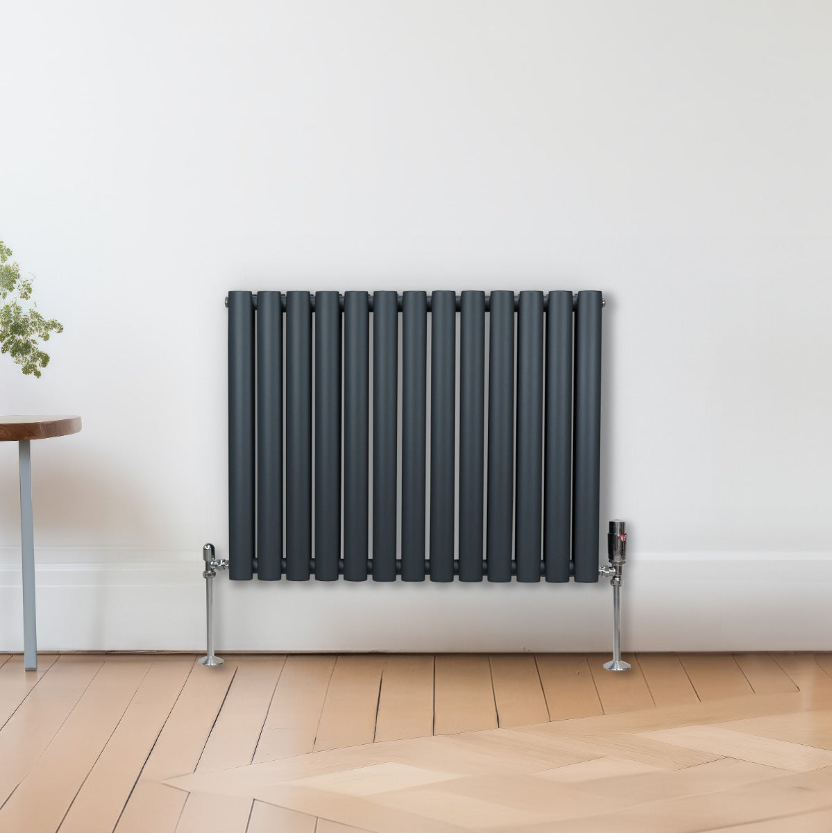 Radiateur à colonnes ovales gris anthracite, 2 panneaux, avec des tuyaux en métal, installé sur un sol en bois clair, design moderne