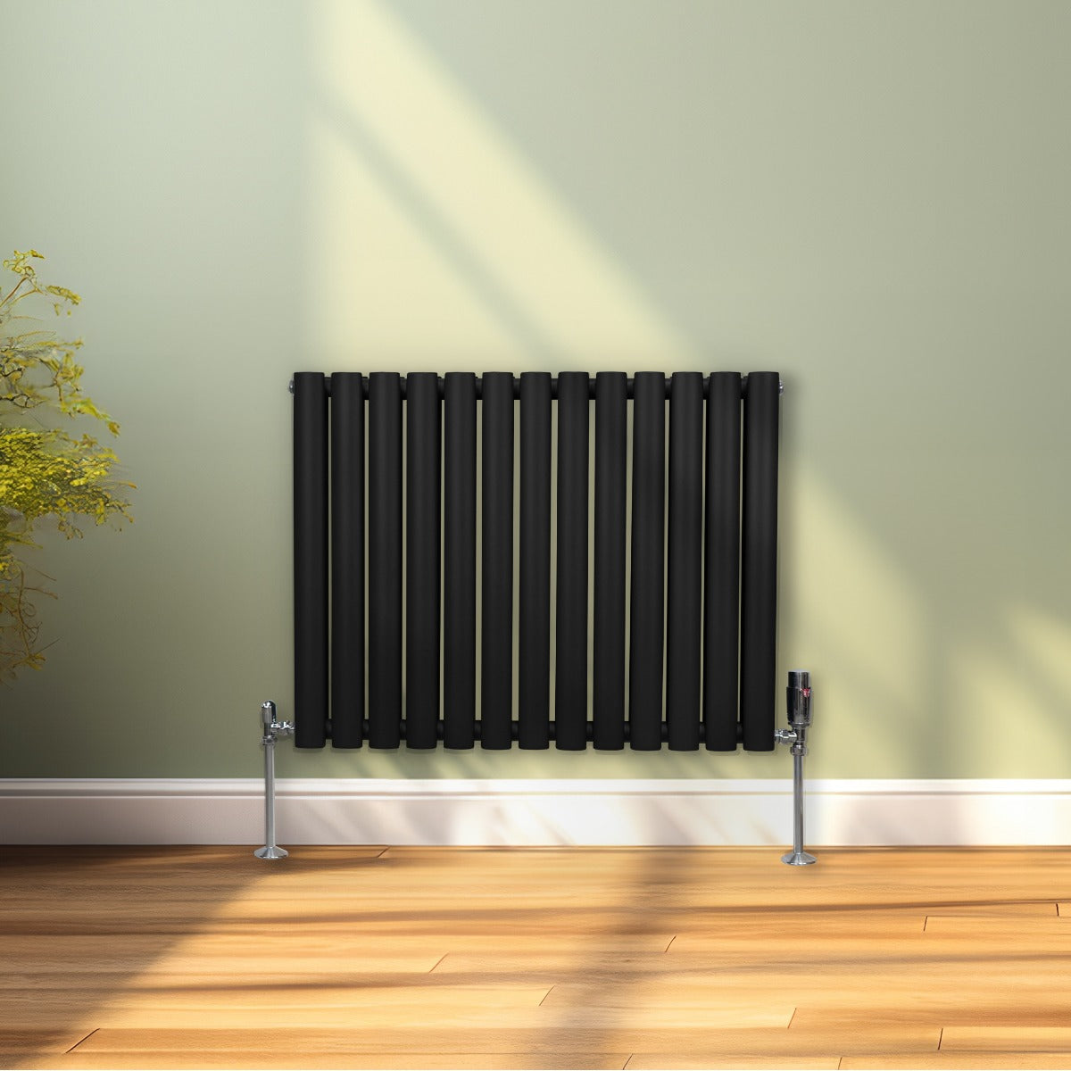 Radiateur à colonnes ovales noir, 2 panneaux, 600 x 780 mm, installé sur un mur clair avec un sol en bois chaleureux et une plante verte