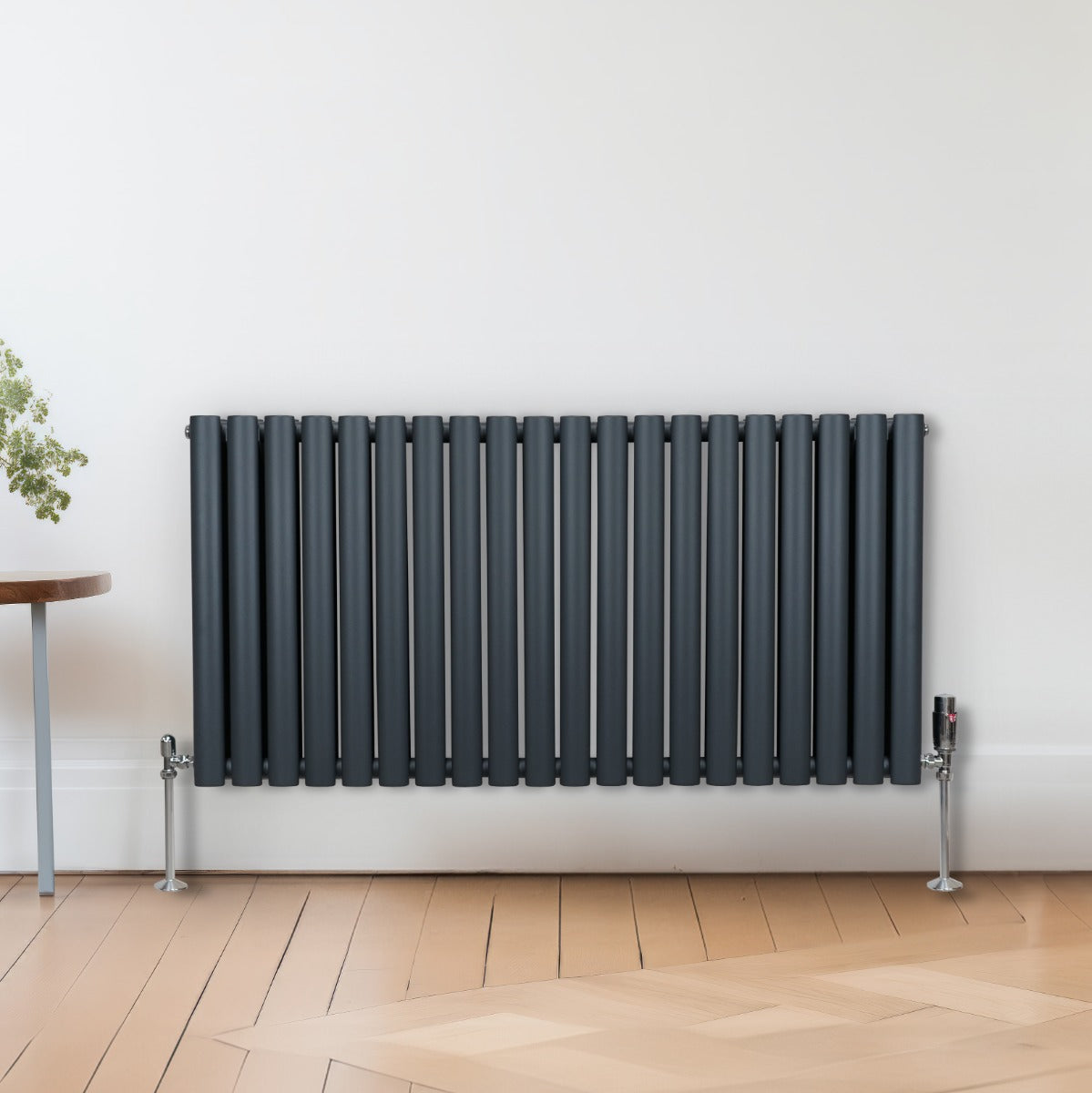 Radiateur à colonnes ovales gris anthracite, 2 panneaux, finition lisse, installé contre un mur, avec sol en bois clair