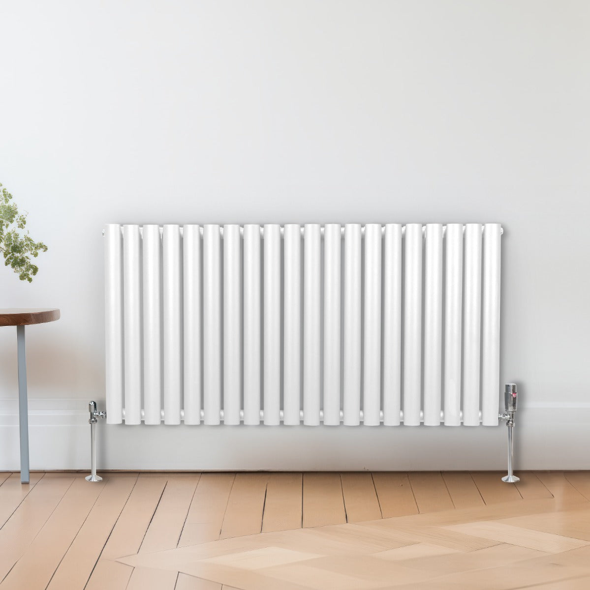 Radiateur à colonnes ovales blanc, 2 panneaux, 600 x 1200 mm, avec pieds chromés, installé sur un sol en bois clair, décor minimaliste