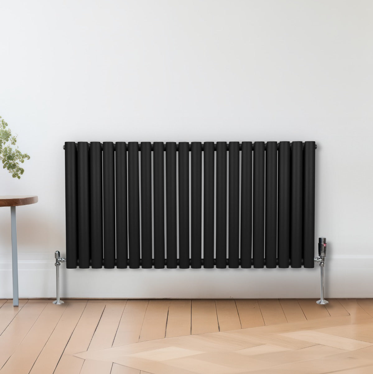 Radiateur à colonnes ovales noir, 2 panneaux, 600 x 1200 mm, avec finition lisse et pieds en métal, installé contre un mur clair