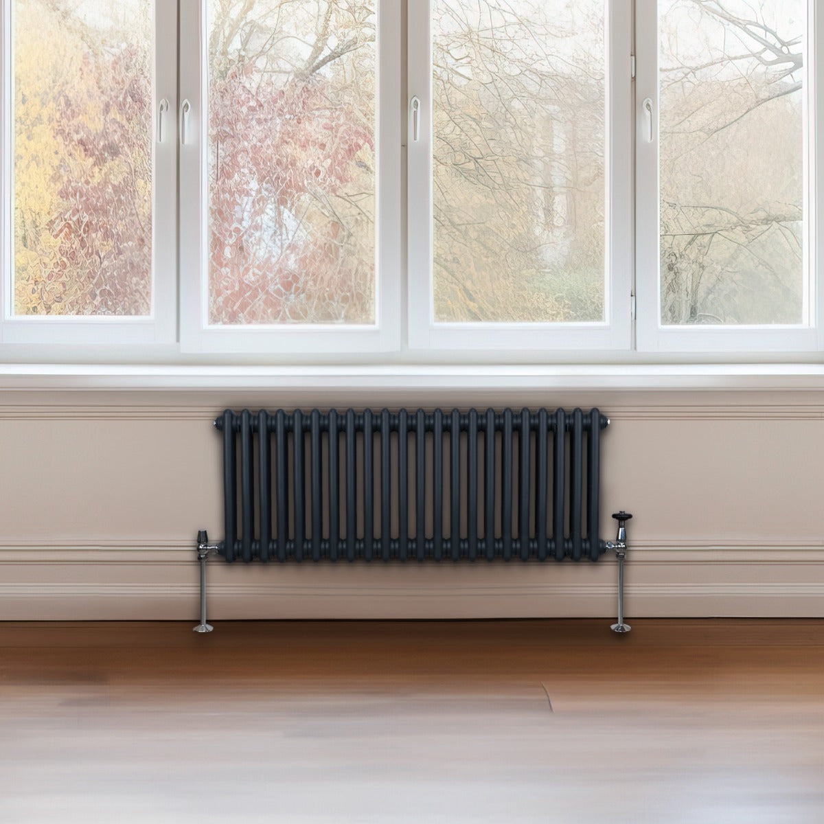 Radiateur traditionnel à 2 colonnes en gris anthracite, installé sous une fenêtre, avec des tuyaux chromés et un design élégant