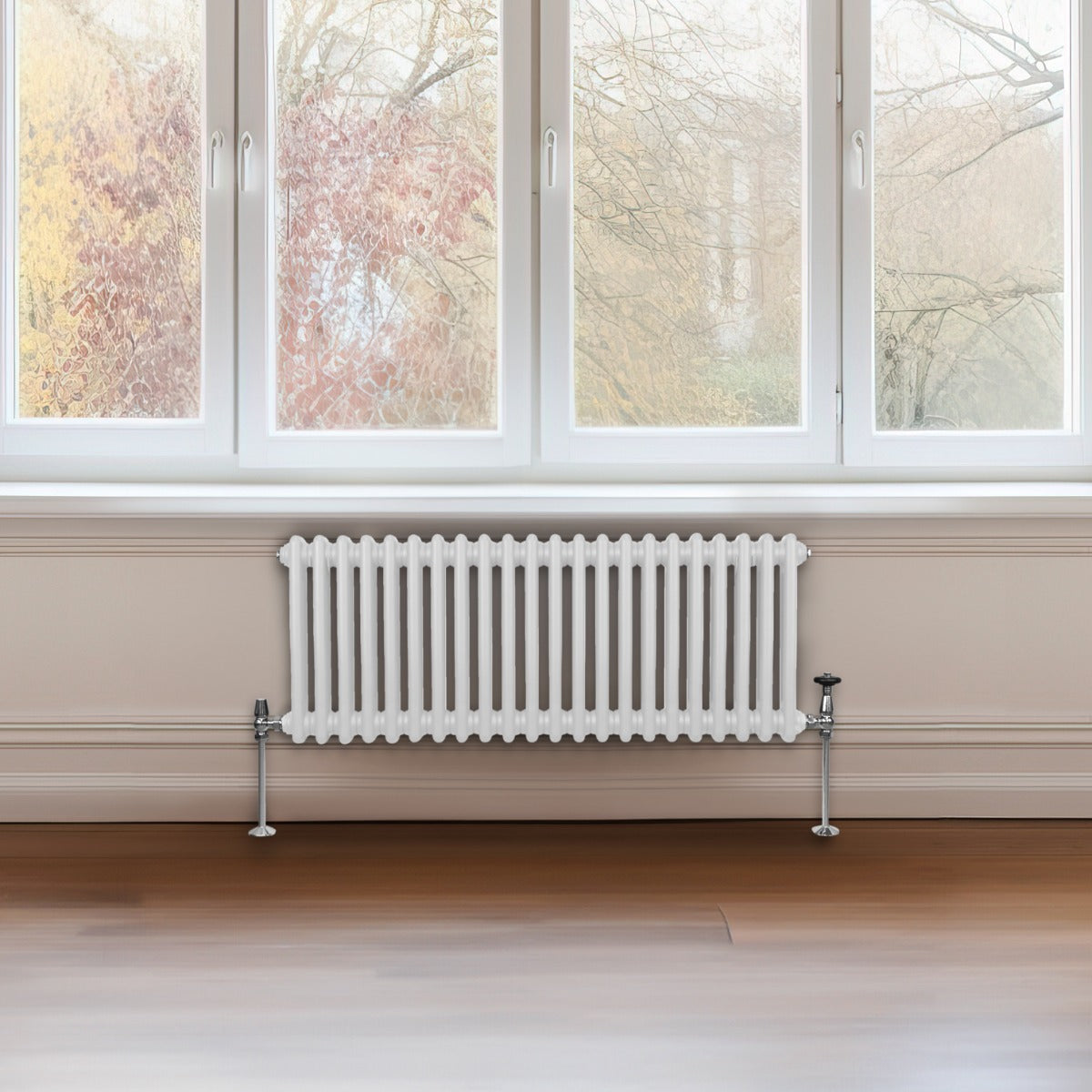 Radiateur traditionnel à 2 colonnes, blanc, installé sous une fenêtre, avec des tuyaux en métal et un sol en bois clair