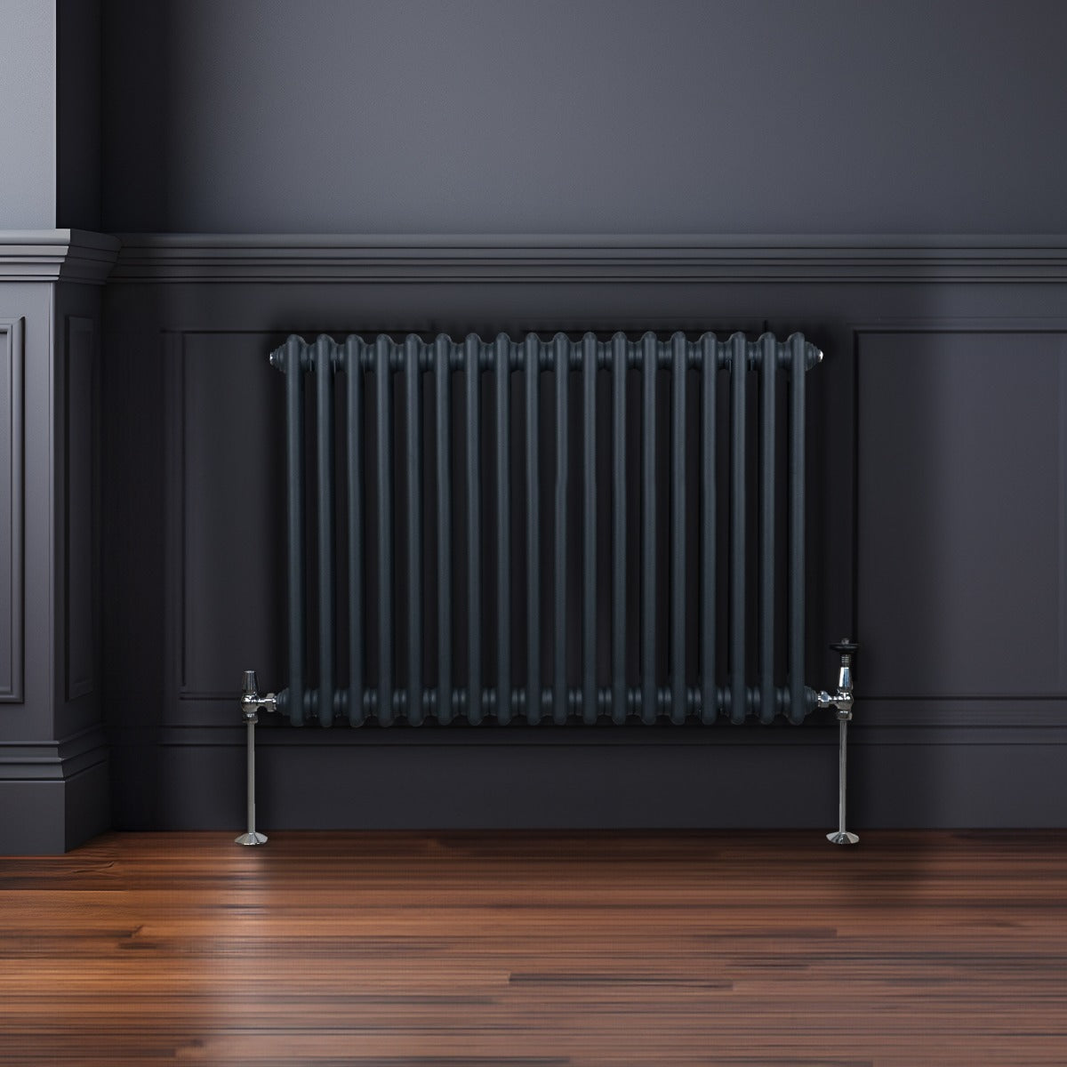 Radiateur traditionnel à 2 colonnes gris anthracite, avec des tubes verticaux lisses et des pieds en métal, sur un mur sombre en bois