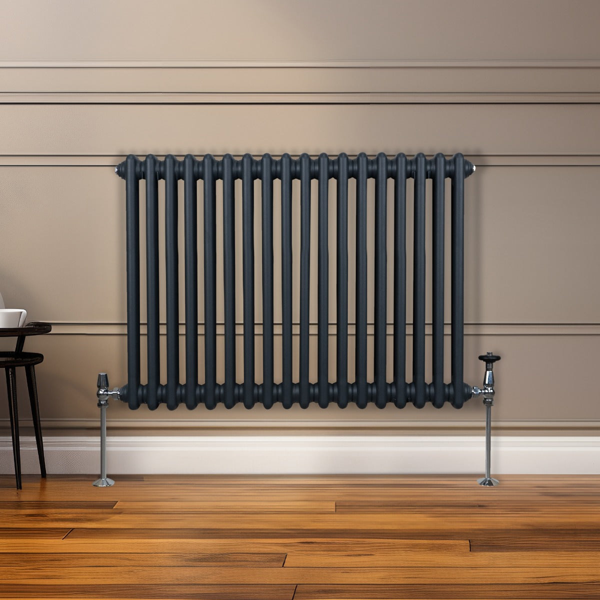 Radiateur traditionnel à deux colonnes gris anthracite, finition lisse, installé sur un mur beige avec un sol en bois chaleureux