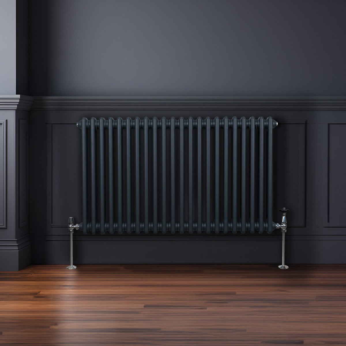 Radiateur traditionnel à deux colonnes gris anthracite, finition lisse, installé contre un mur sombre, avec sol en bois chaleureux