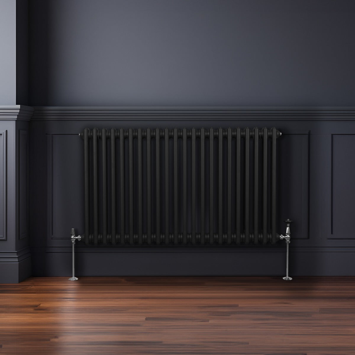 Radiateur traditionnel noir à deux colonnes, 600 x 1012 mm, installé contre un mur sombre avec un sol en bois élégant