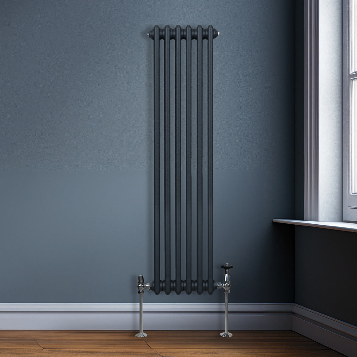 Radiateur traditionnel à 2 colonnes gris anthracite, finition lisse, installé contre un mur, avec des tuyaux chromés et un sol en bois clair