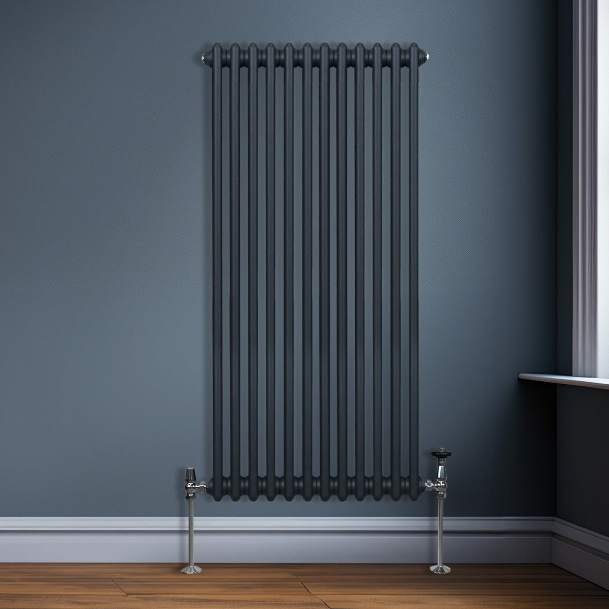 Radiateur traditionnel à 2 colonnes en gris anthracite, avec une finition lisse, installé contre un mur bleu, sur un sol en bois clair