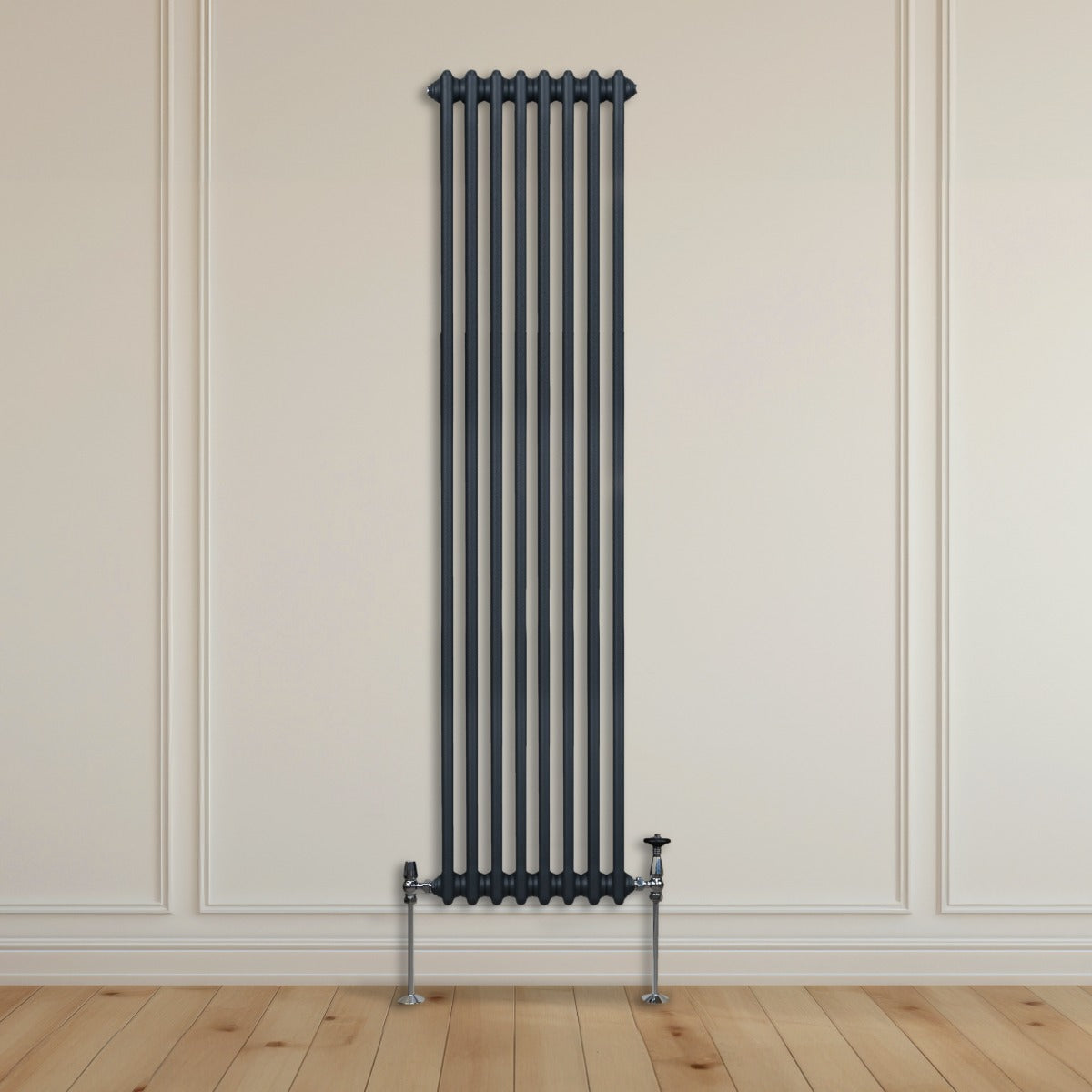Radiateur traditionnel à 2 colonnes, gris anthracite, installé sur un mur clair, avec des pieds en métal et un sol en bois naturel