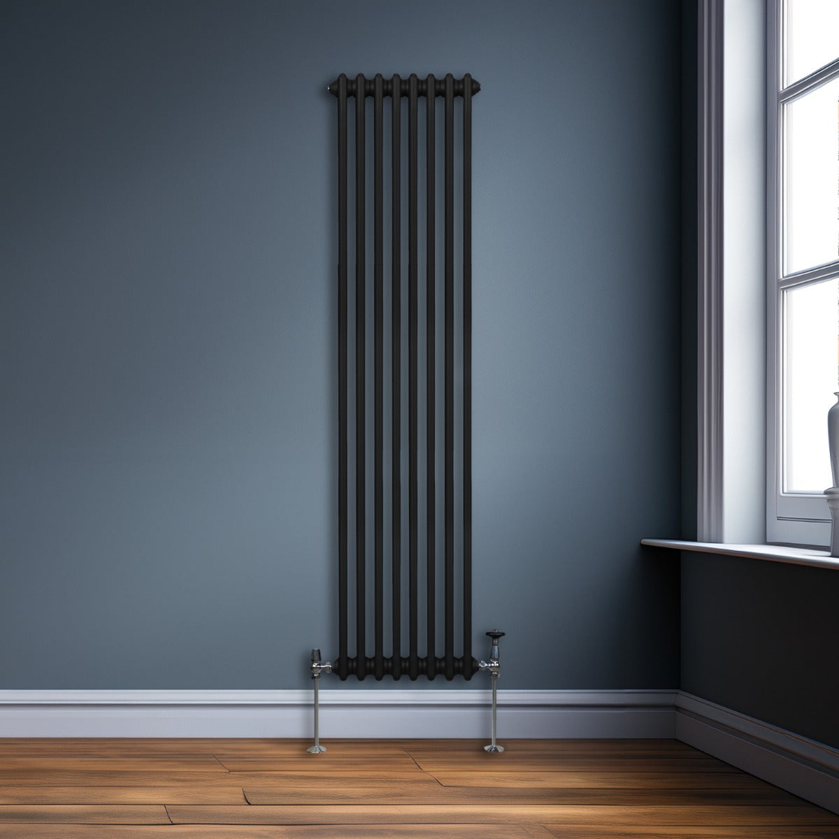 Radiateur traditionnel noir à deux colonnes, 1800 x 382 mm, installé contre un mur bleu, avec un sol en bois clair et une fenêtre lumineuse