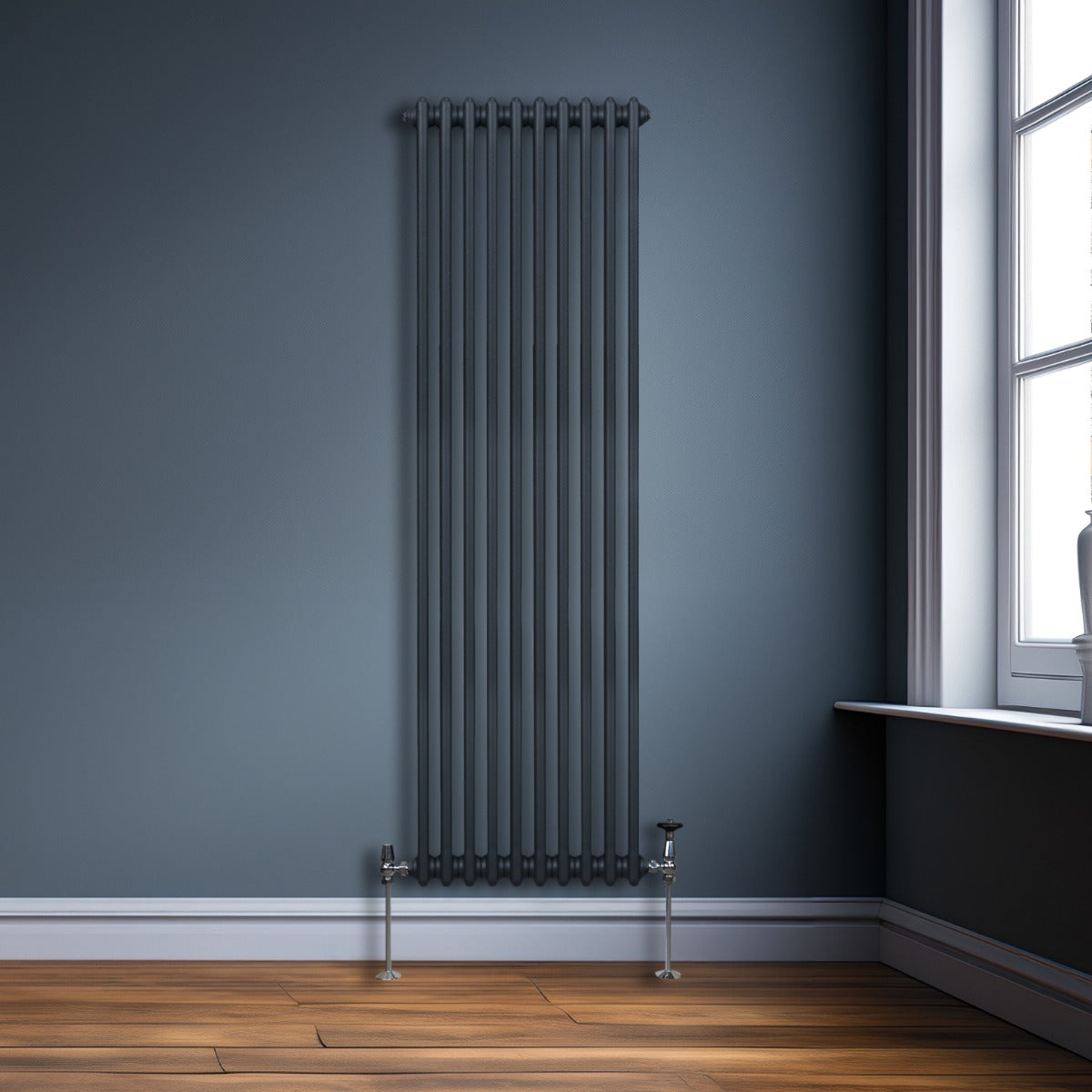Radiateur traditionnel à deux colonnes, gris anthracite, finition lisse, installé contre un mur bleu, avec un sol en bois chaleureux