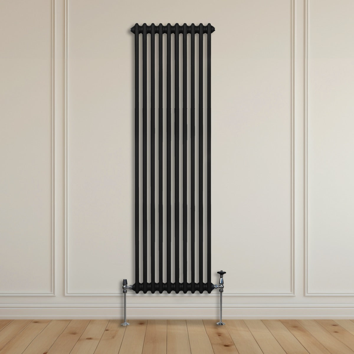 Radiateur traditionnel noir à deux colonnes, 1800 x 472 mm, installé contre un mur avec un sol en bois clair et des tuyaux chromés visibles