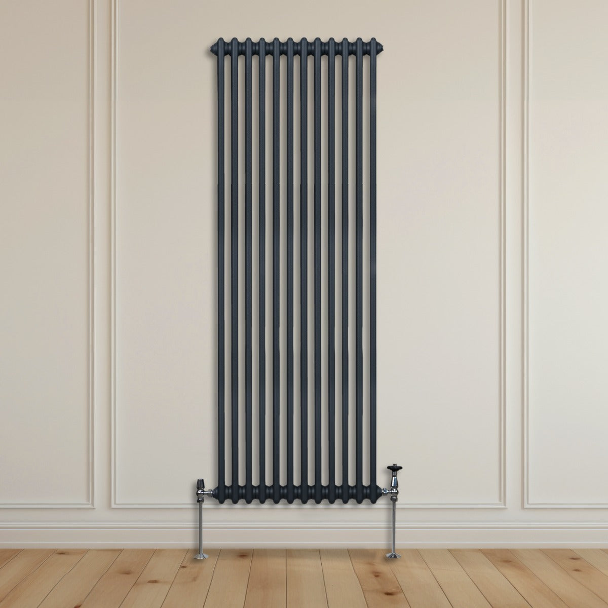 Radiateur traditionnel à deux colonnes gris anthracite, haut et étroit, installé contre un mur avec un sol en bois clair
