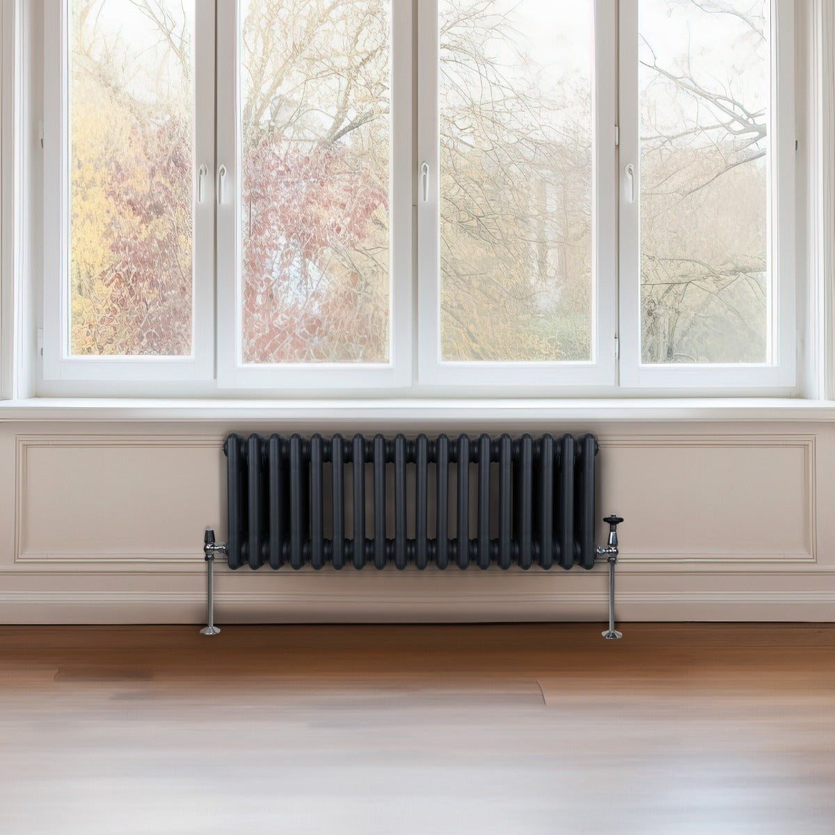 Radiateur traditionnel à 3 colonnes gris anthracite, installé sous une fenêtre, avec un design élégant et moderne, sur un sol en bois clair
