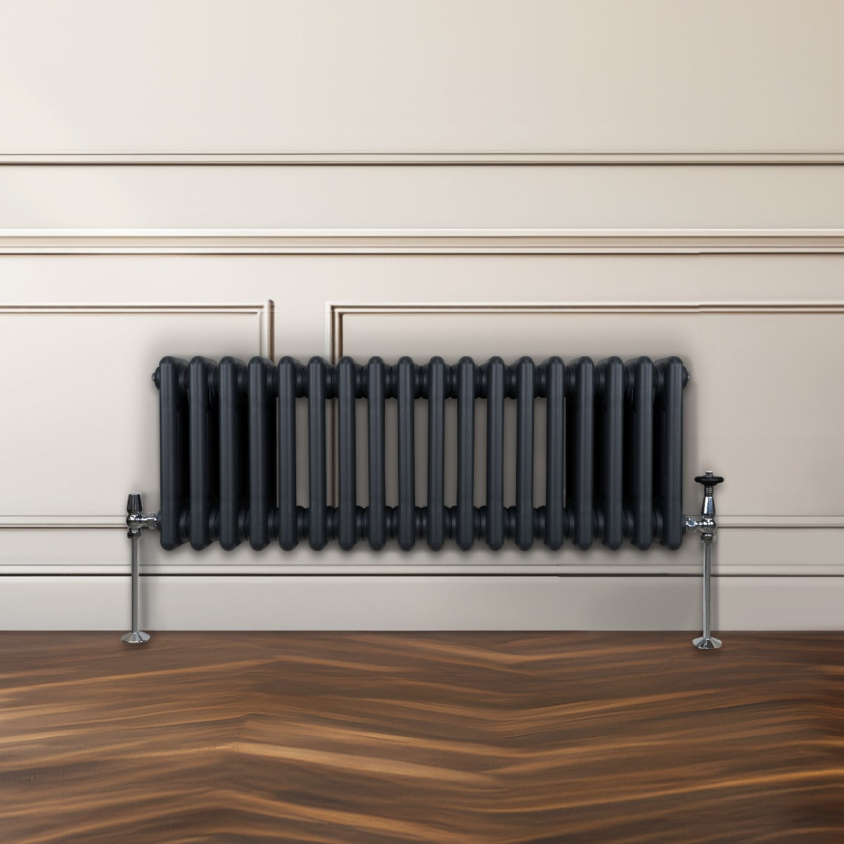Radiateur traditionnel à 3 colonnes gris anthracite, installé contre un mur, avec des pieds en métal et un sol en bois texturé