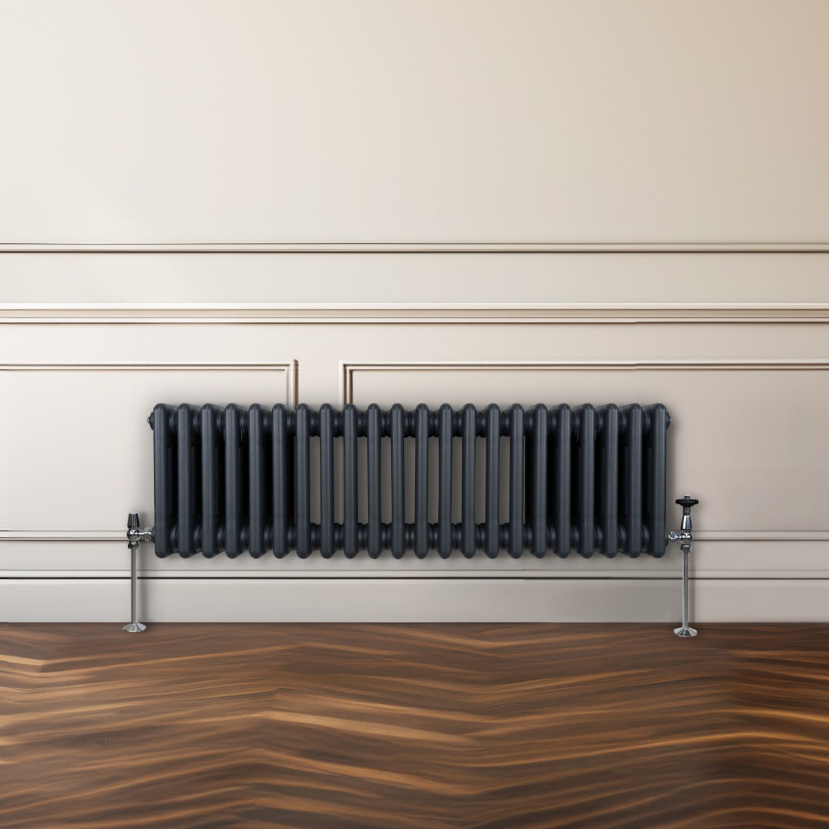 Radiateur traditionnel à 3 colonnes gris anthracite, finition lisse, installé contre un mur beige, avec des pieds en métal brillant