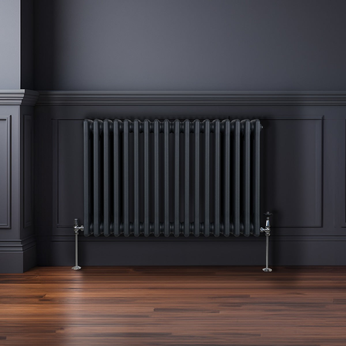 Radiateur traditionnel à 3 colonnes gris anthracite, installé contre un mur sombre, avec un sol en bois chaleureux et élégant