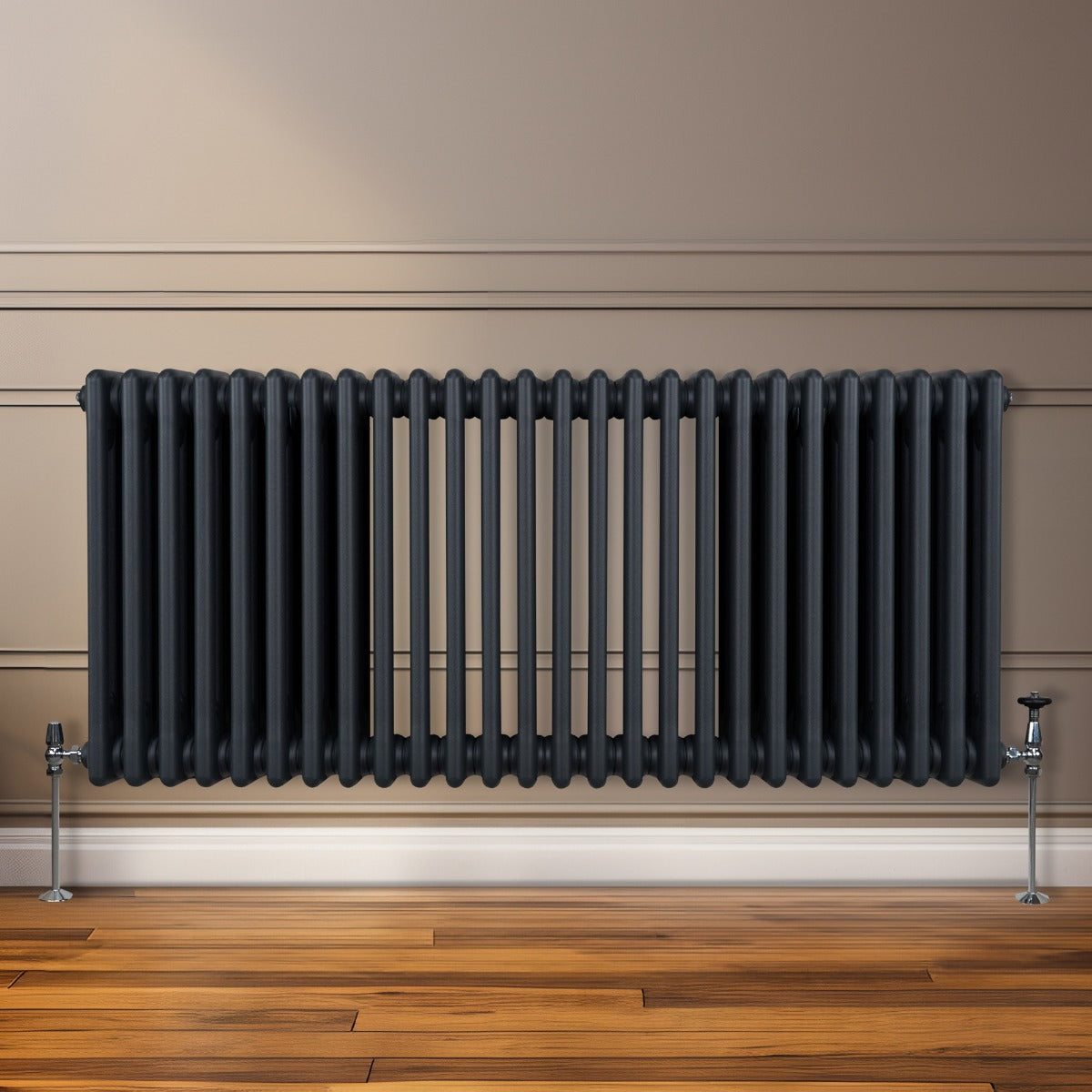 Radiateur traditionnel à 3 colonnes, gris anthracite, installé contre un mur, avec une finition lisse et des pieds en métal brillant