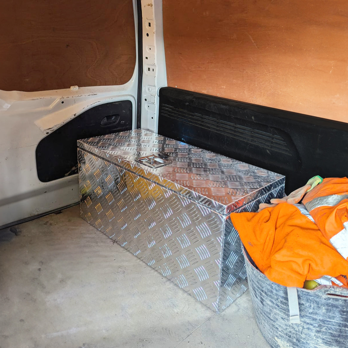 Caisse à outils en aluminium de 102 L, finition en relief, brillante, placée dans un véhicule utilitaire, entourée de matériel de travail