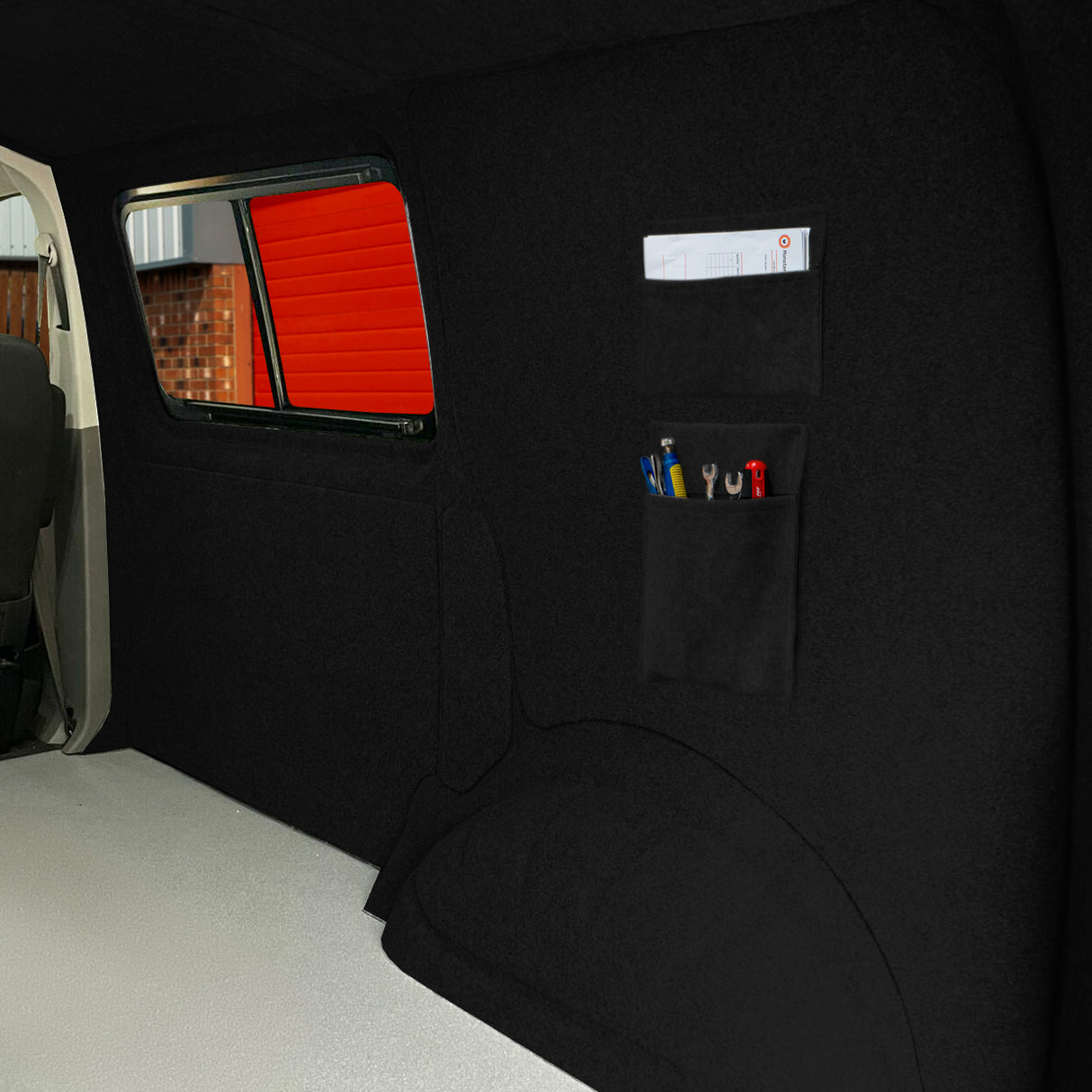 Poches de rangement noires en tissu, fixées à un mur intérieur, offrant un espace organisé pour outils et fournitures, avec une texture douce