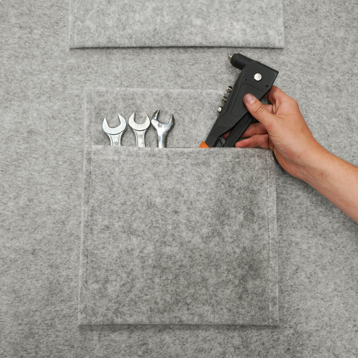 Poches de rangement gris argenté en feutre, contenant des clés à molette et un pistolet à colle, offrant une organisation pratique