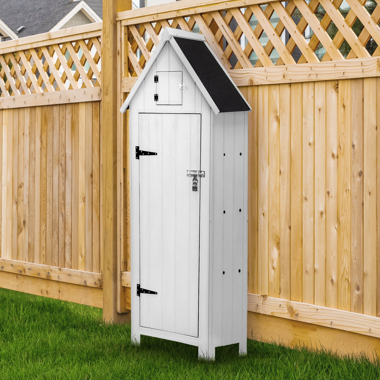Abri de jardin en bois blanc avec toit noir, portes battantes et finition lisse, situé près d'une clôture en bois et sur pelouse verte