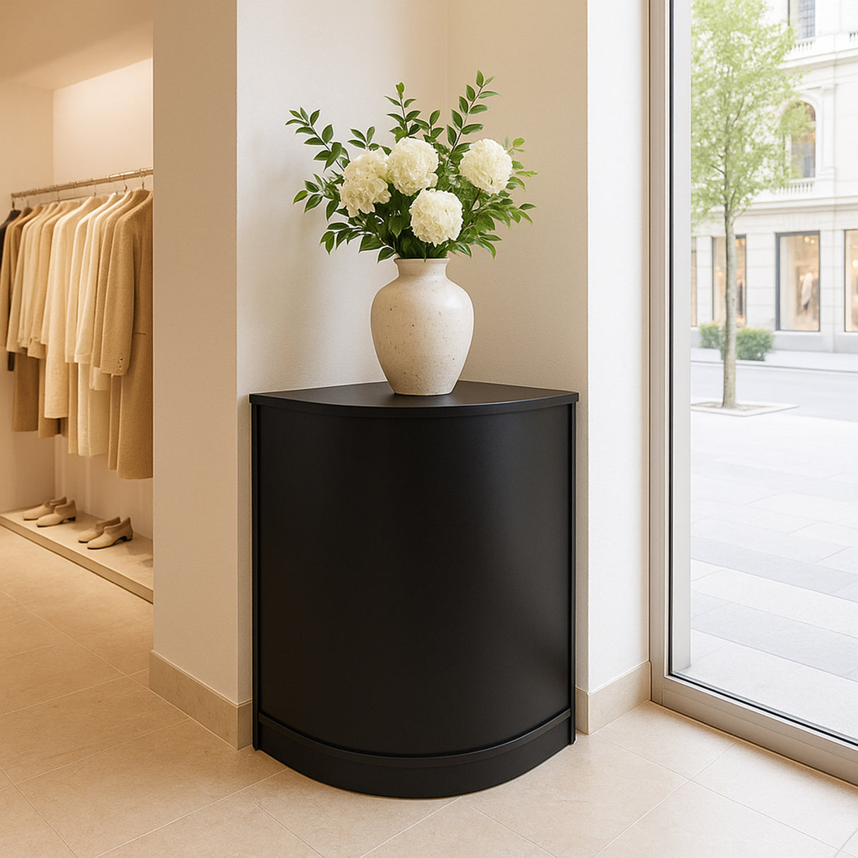 Vitrine de coin noire élégante avec vase en céramique blanche, fleurs blanches et feuillage, dans un espace lumineux et moderne