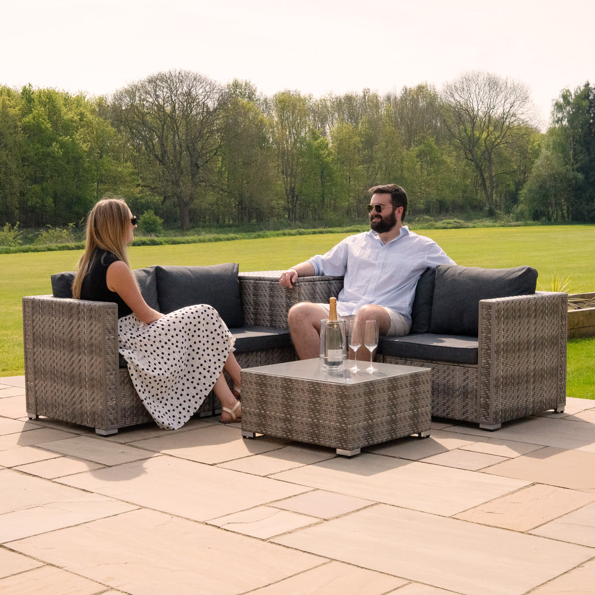 Salon de jardin modulaire en rotin gris, composé de canapés confortables et d'une table basse, idéal pour les espaces extérieurs