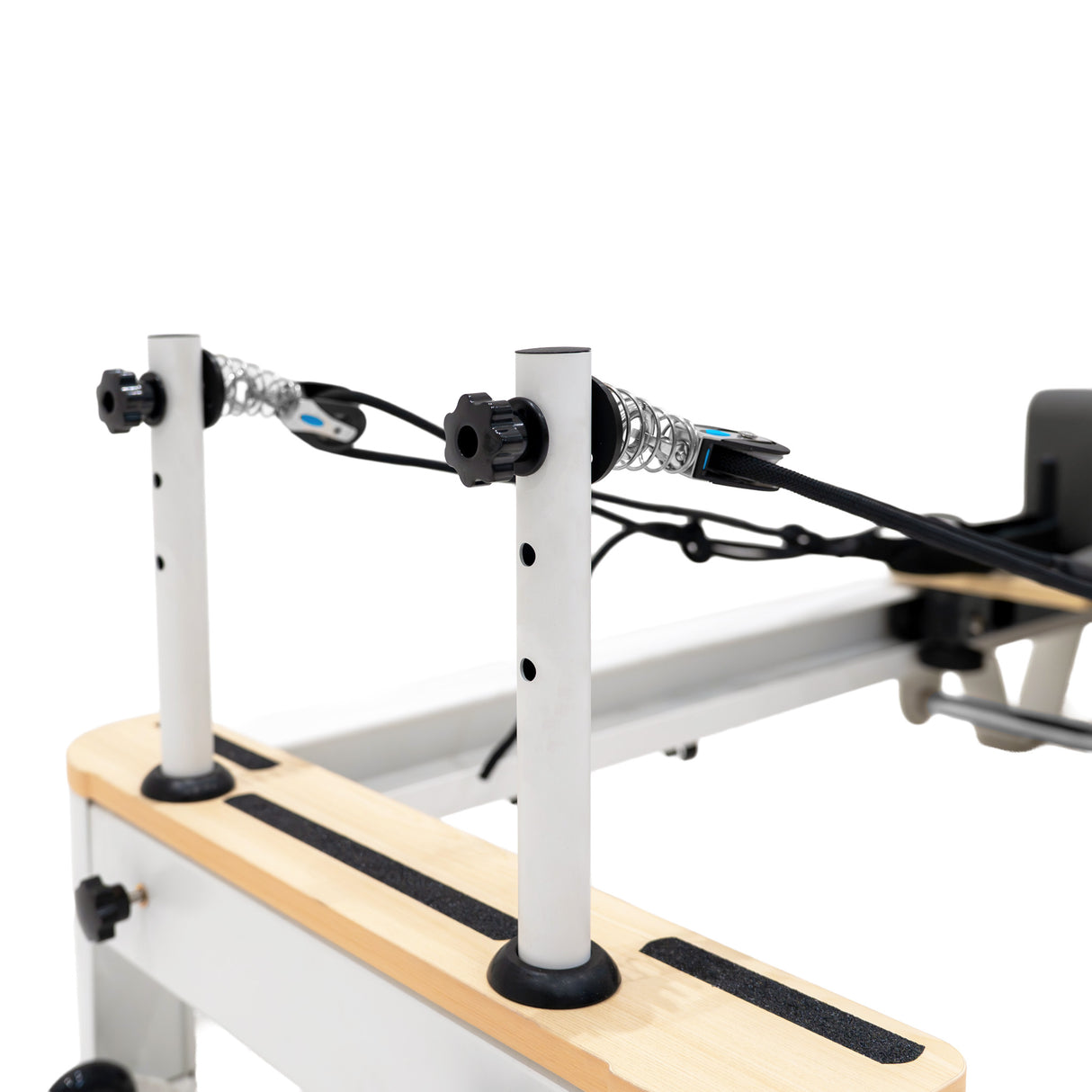Machine reformer Pilates pliable en aluminium, avec des barres blanches, des poignées en caoutchouc noir et un plateau en bois clair