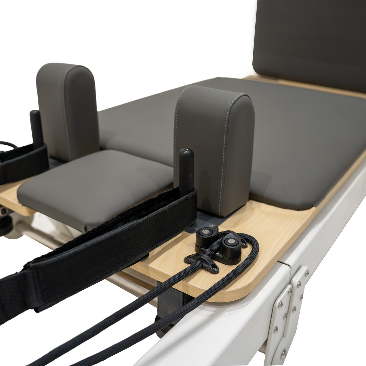 Reformer Pilates pliable en aluminium avec coussins gris, sangles noires et surface en bois clair, idéal pour l'exercice et le confort