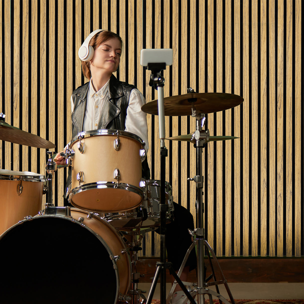 Panneaux lattes acoustiques muraux en chêne, présentant des lignes verticales, créant une ambiance chaleureuse et moderne dans un studio de musique