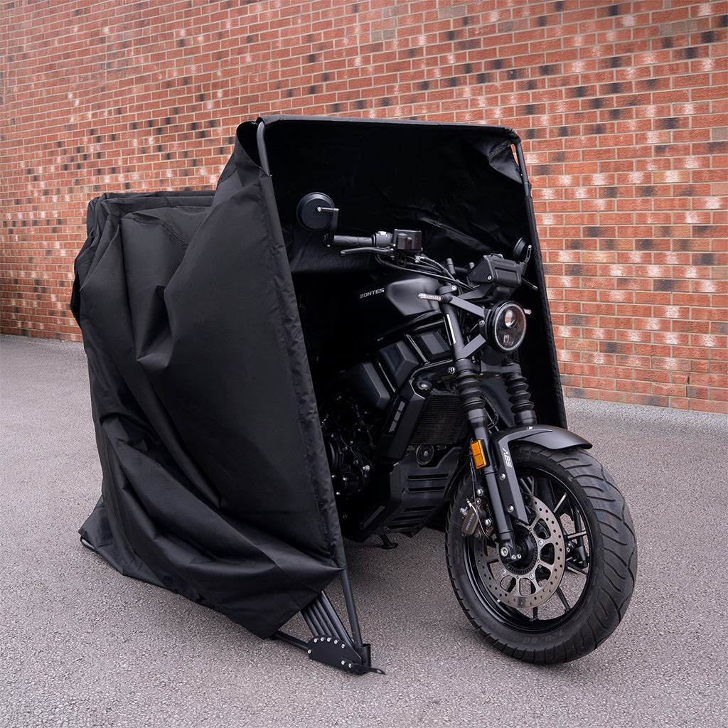 Moto noire moderne protégée par une housse noire, avec un fond en briques rouges, offrant une protection contre les intempéries
