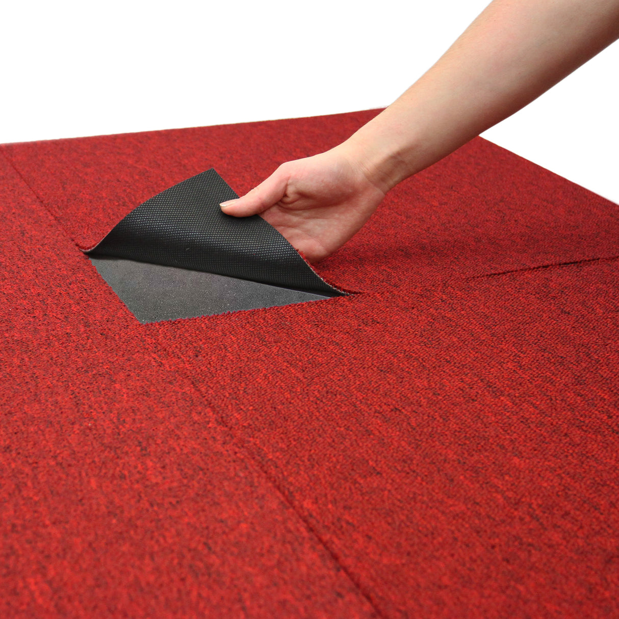 Dalle de moquette rouge écarlate de 50 cm x 50 cm, texture douce, main soulevant un coin pour révéler le dessous noir, idéal pour décoration intérieure