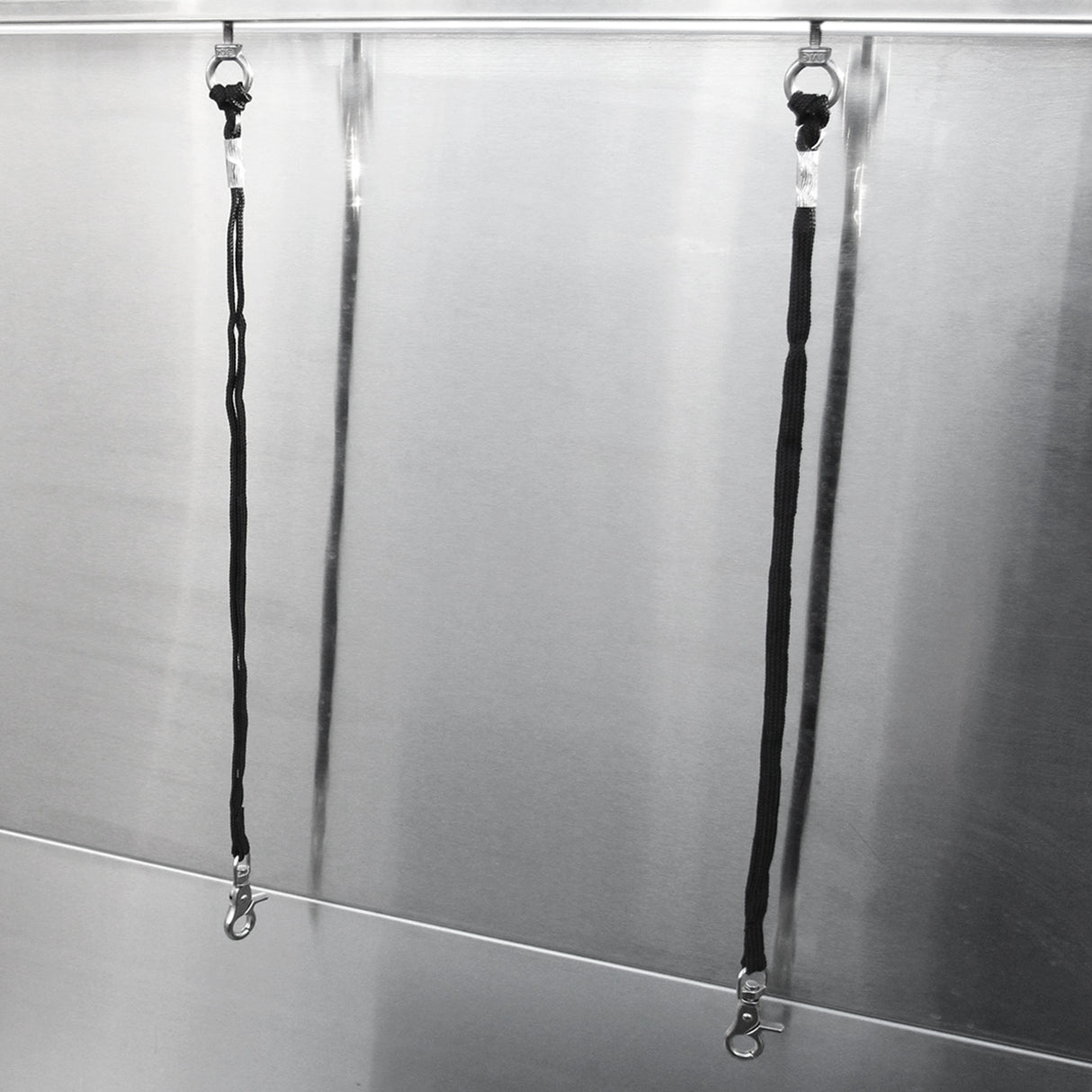 Câbles de maintien en nylon noir fixés à une baignoire de toilettage en inox, offrant robustesse et sécurité pour le bain des animaux
