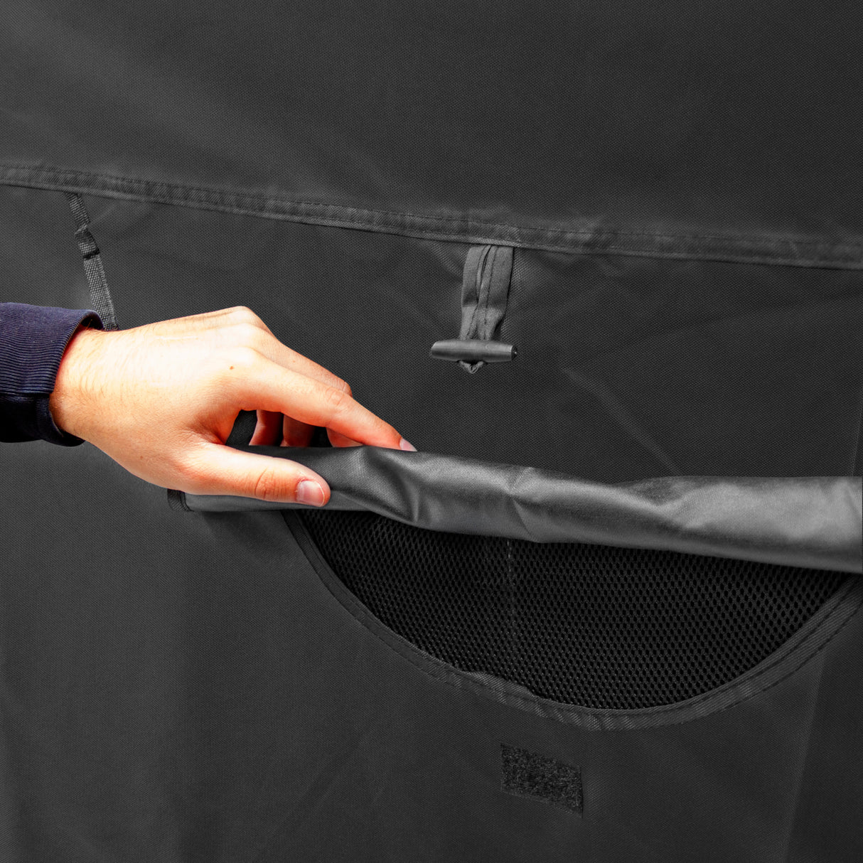 Tente de rangement XL pour moto en tissu noir résistant, avec une poche en maille et une main tenant le rabat supérieur