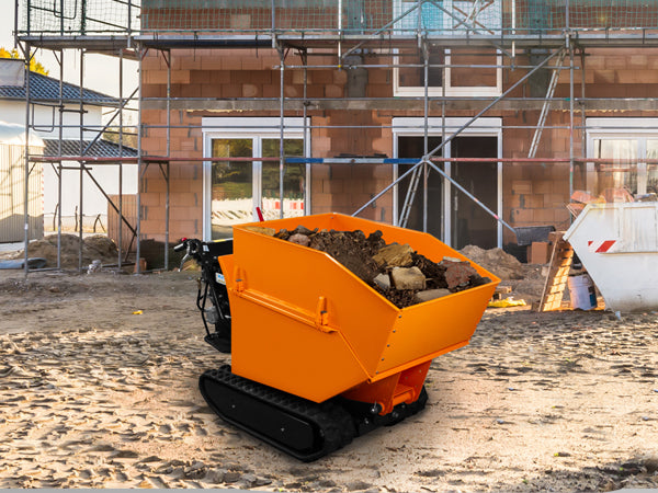 Mini dumper orange sur un chantier, rempli de terre et de pierres, avec un bâtiment en construction en arrière-plan et des échafaudages