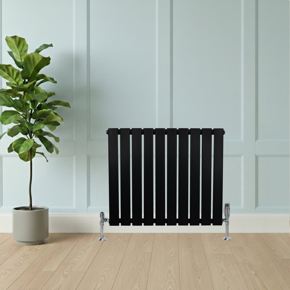 Radiateur plat noir à un panneau, 600 x 700 mm, avec vannes, installé devant un mur clair et un sol en bois, décoré d'une plante verte