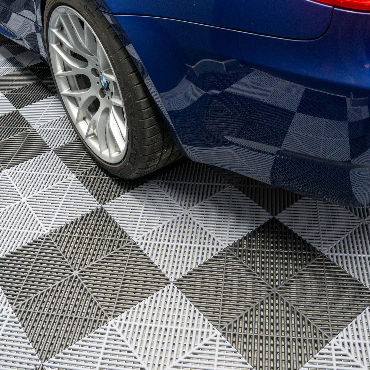 Carrelage de sol ventilé noir et gris pour garage, avec texture en relief, supportant le poids d'une voiture sur des dalles modulaires