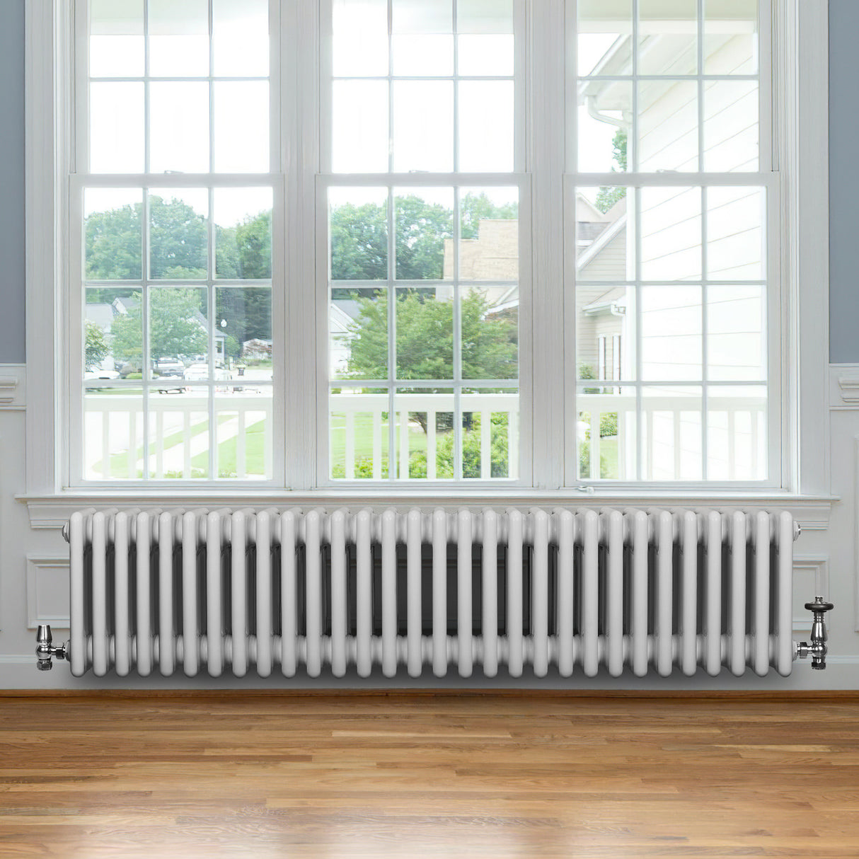 Radiateur traditionnel à 4 colonnes blanc, 300 x 1370 mm, installé sous une fenêtre, avec un sol en bois clair et un cadre moderne