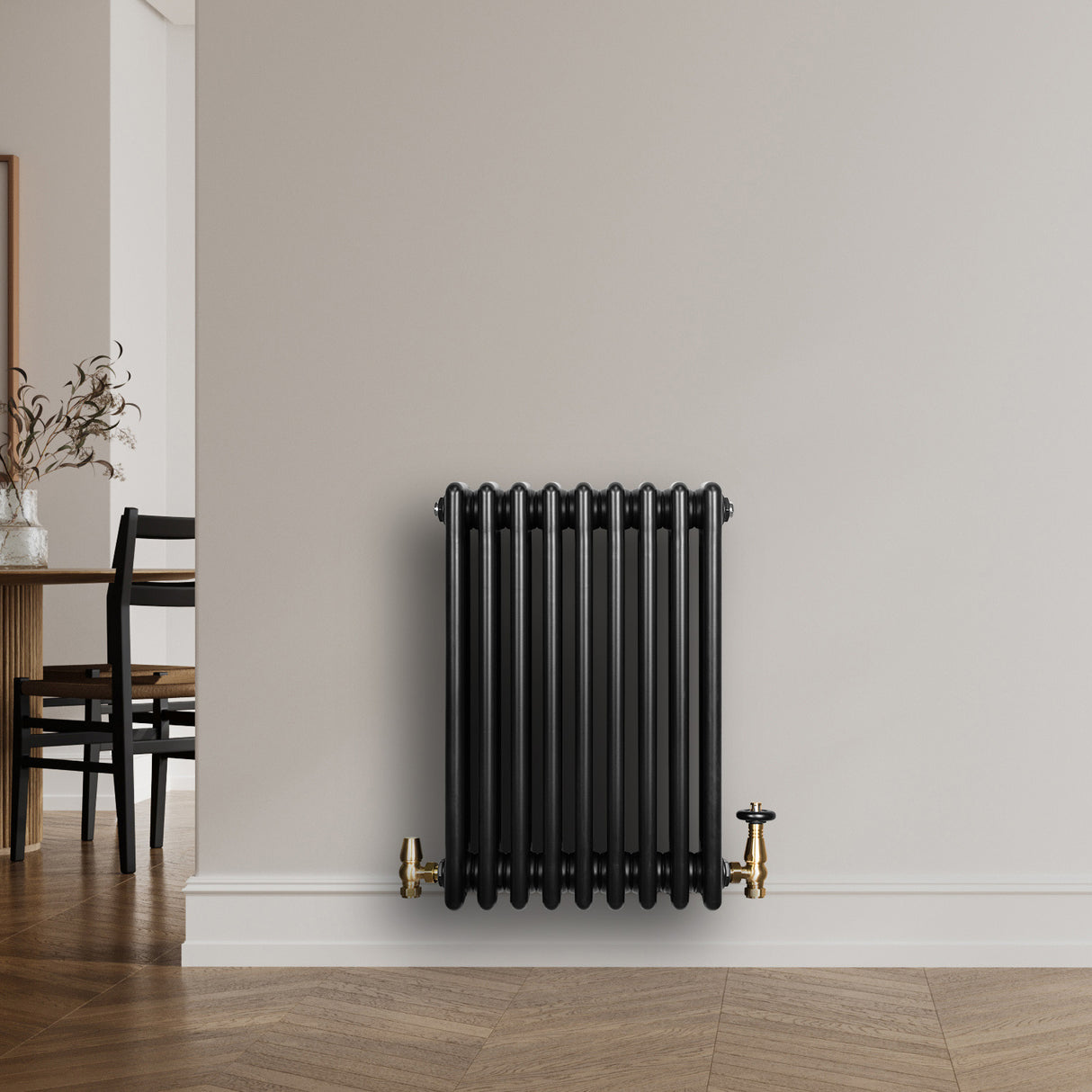 Radiateur traditionnel noir à 4 colonnes, finition lisse, installé contre un mur, avec des robinets en laiton doré, décor moderne