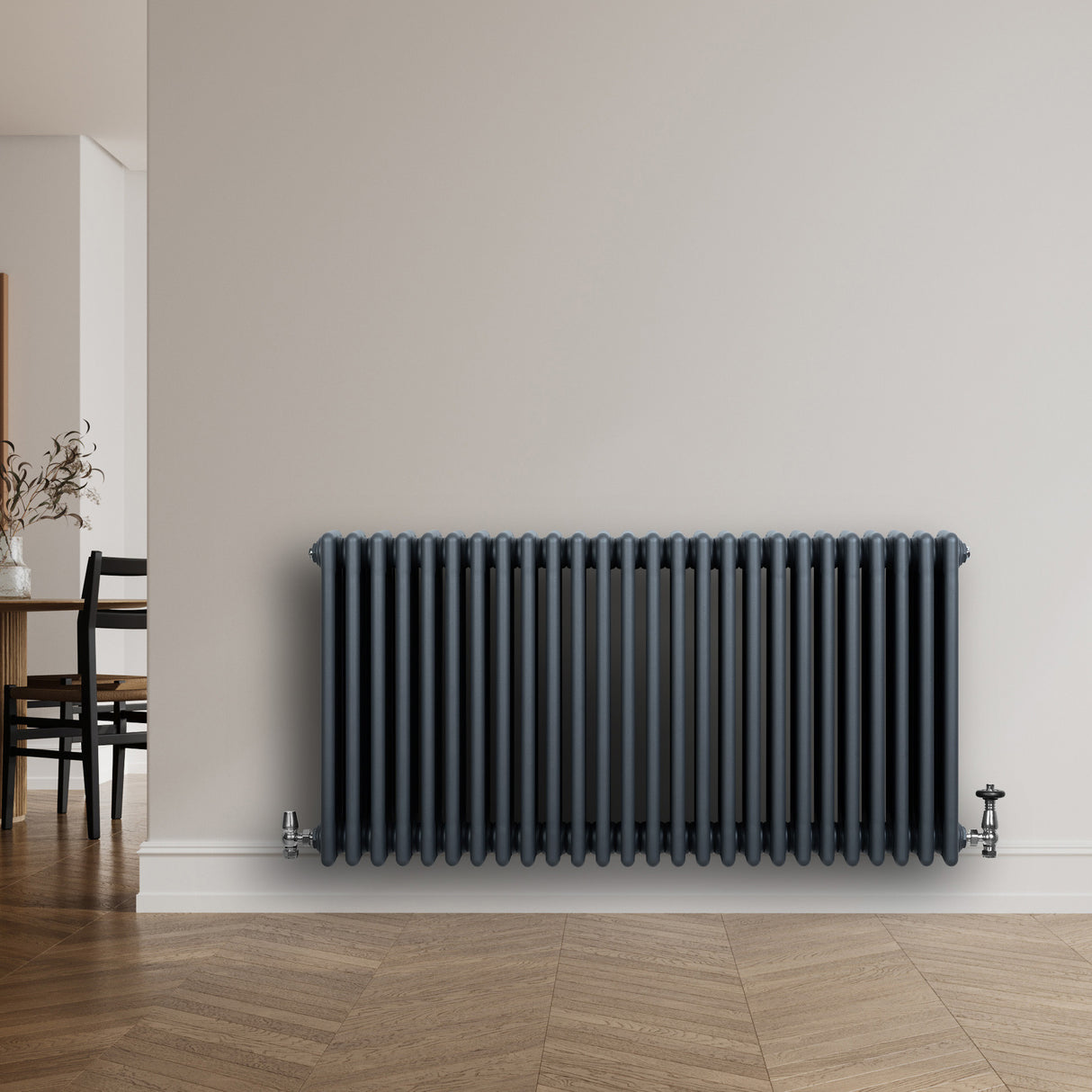 Radiateur traditionnel à 4 colonnes gris anthracite, finition lisse, installé sur un mur clair, avec un sol en bois chaleureux