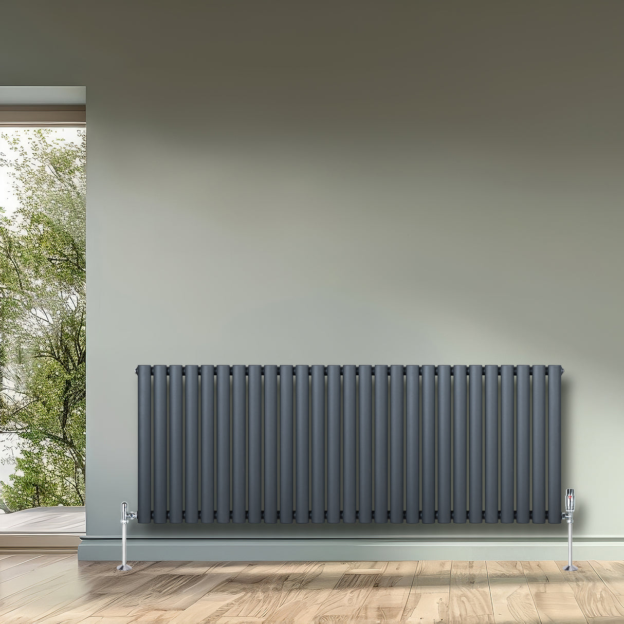 Radiateur à colonnes ovales gris anthracite, 600 x 1620 mm, installé sur un mur, avec un sol en bois clair et une vue sur l'extérieur